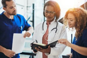 three healthcare professionals look at a paper