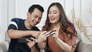 man and woman smile and point at phones as they use technology to connect during coronavirus