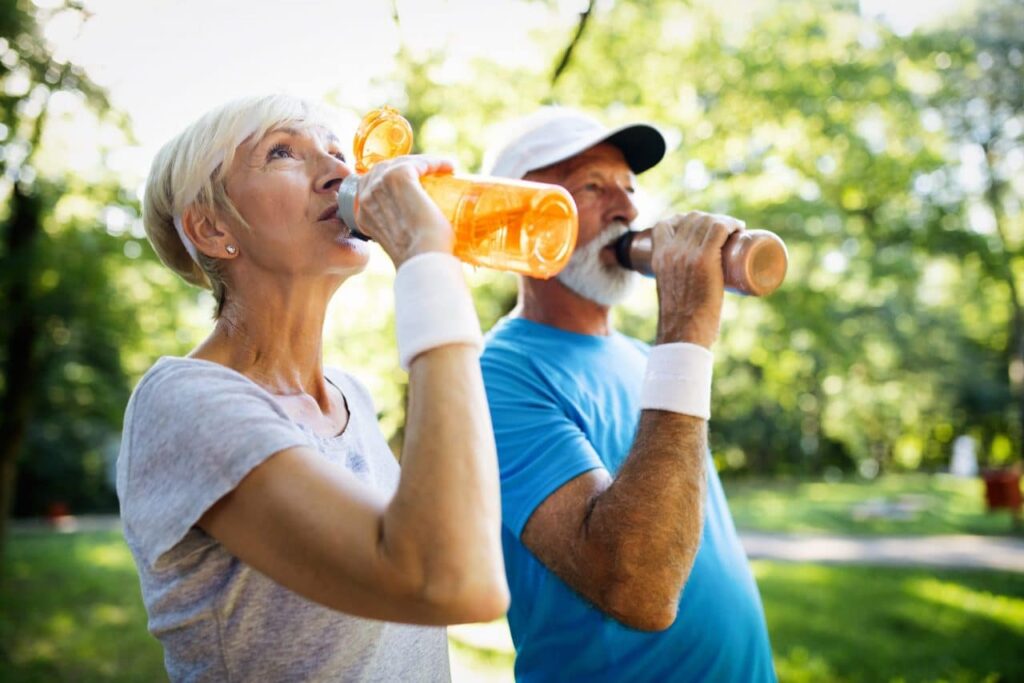 Old couple drinking water while on a walk