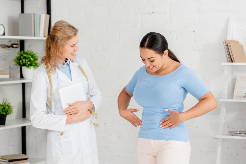 Woman touching stomach for signs of kidney transplant rejection