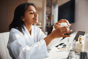 Cheerful woman using cream on her skin